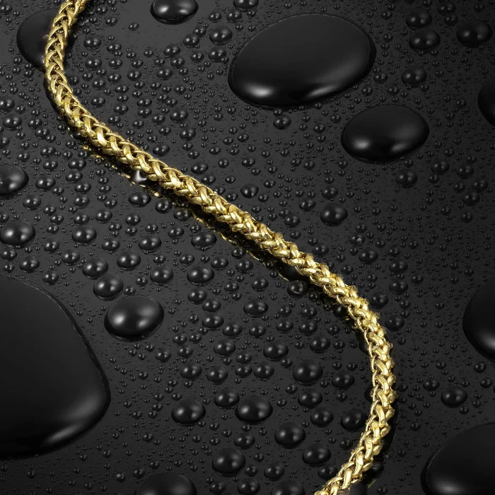 Gold chain on a black surface with water droplets