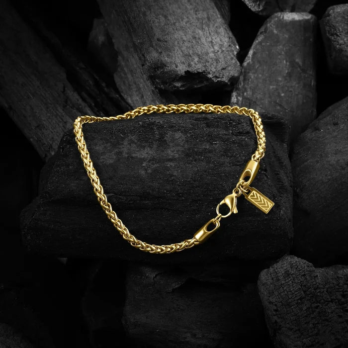 Gold chain bracelet with a tag on dark stone background